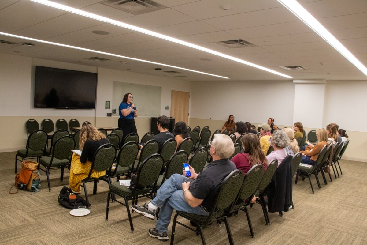 A person standing at the front of a room talking into a microphone.