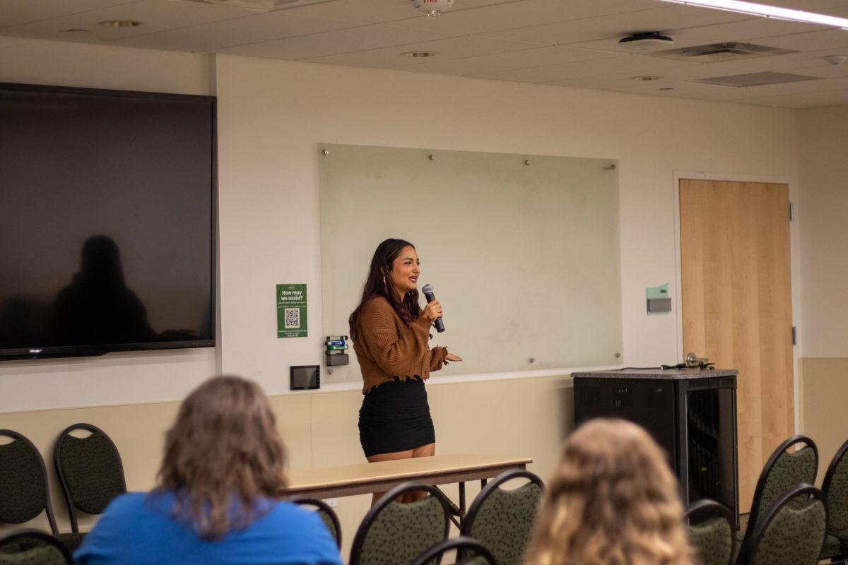 A person standing at the front of a room talking into a microphone.