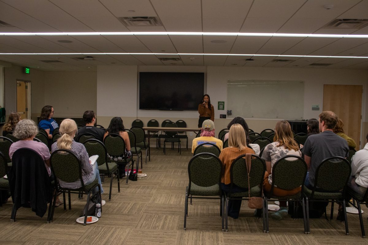 A person standing at the front of a room talking into a microphone.