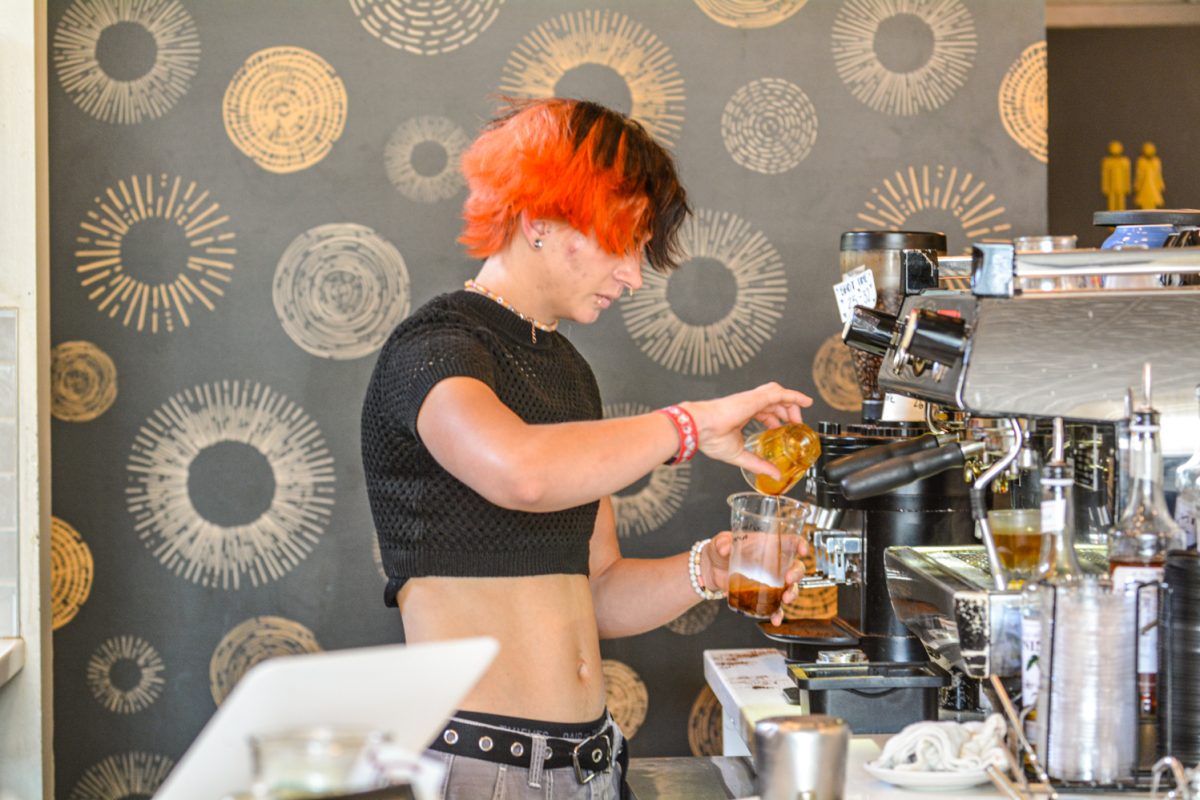 A barista pouring espresso into a big cup