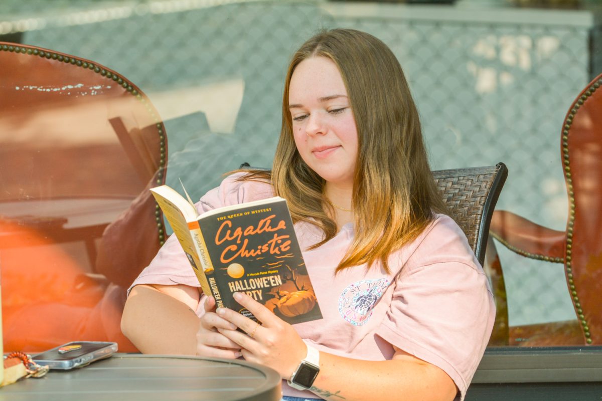 A woman reading a book outside of a coffee shop