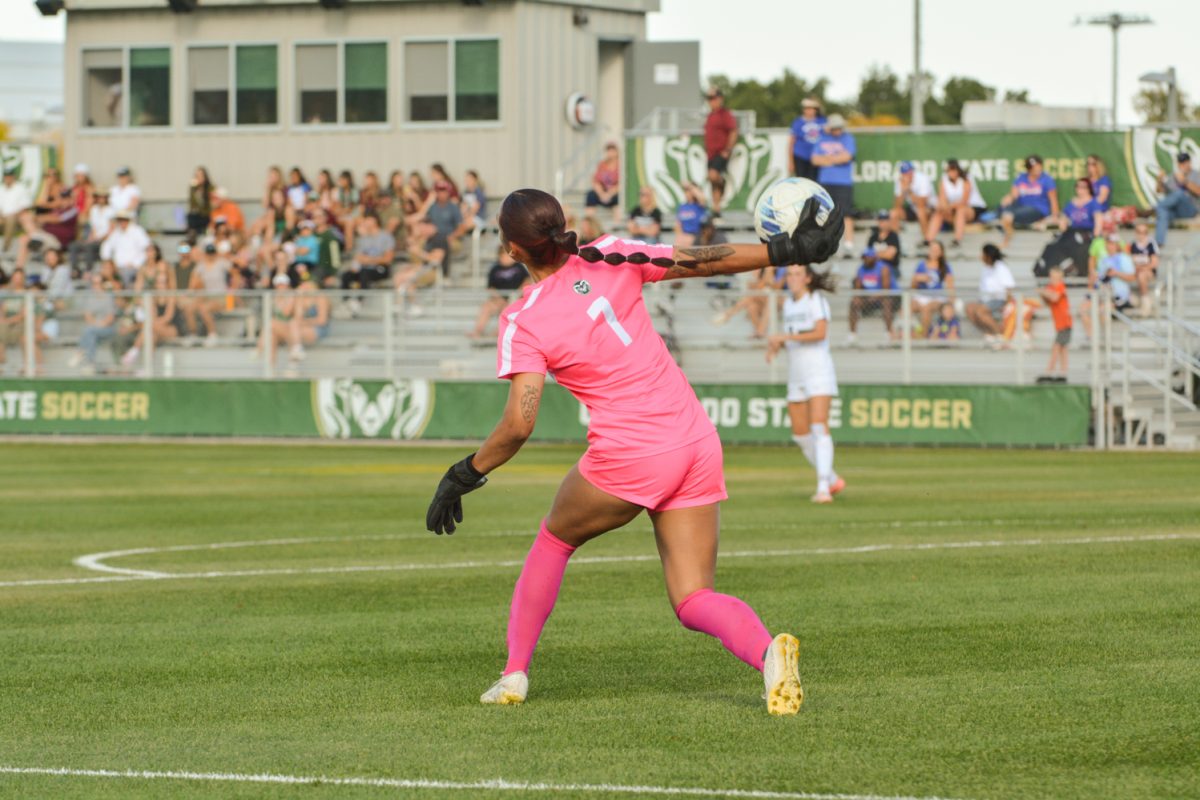 A soccer player in a bright pink jersey throwing a ball