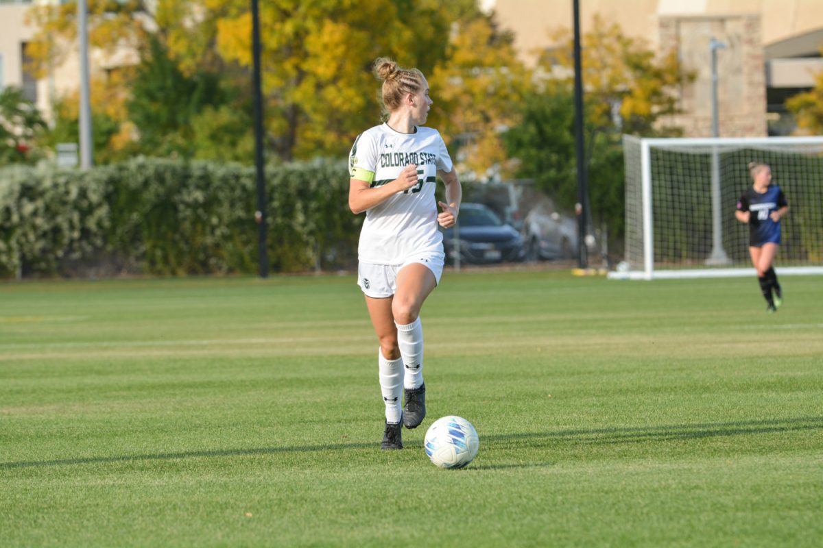 A soccer player kicking the ball looking back at her teammates