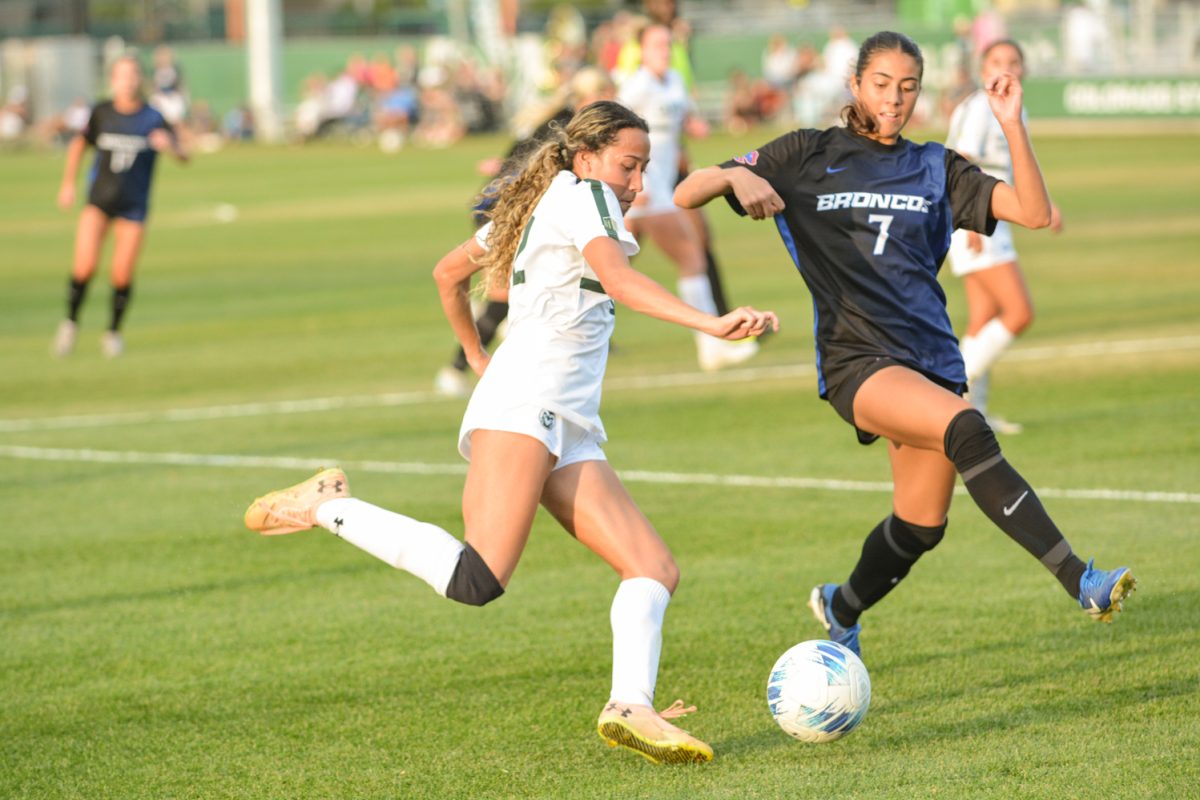 Two soccer players fighting over the soccer ball.