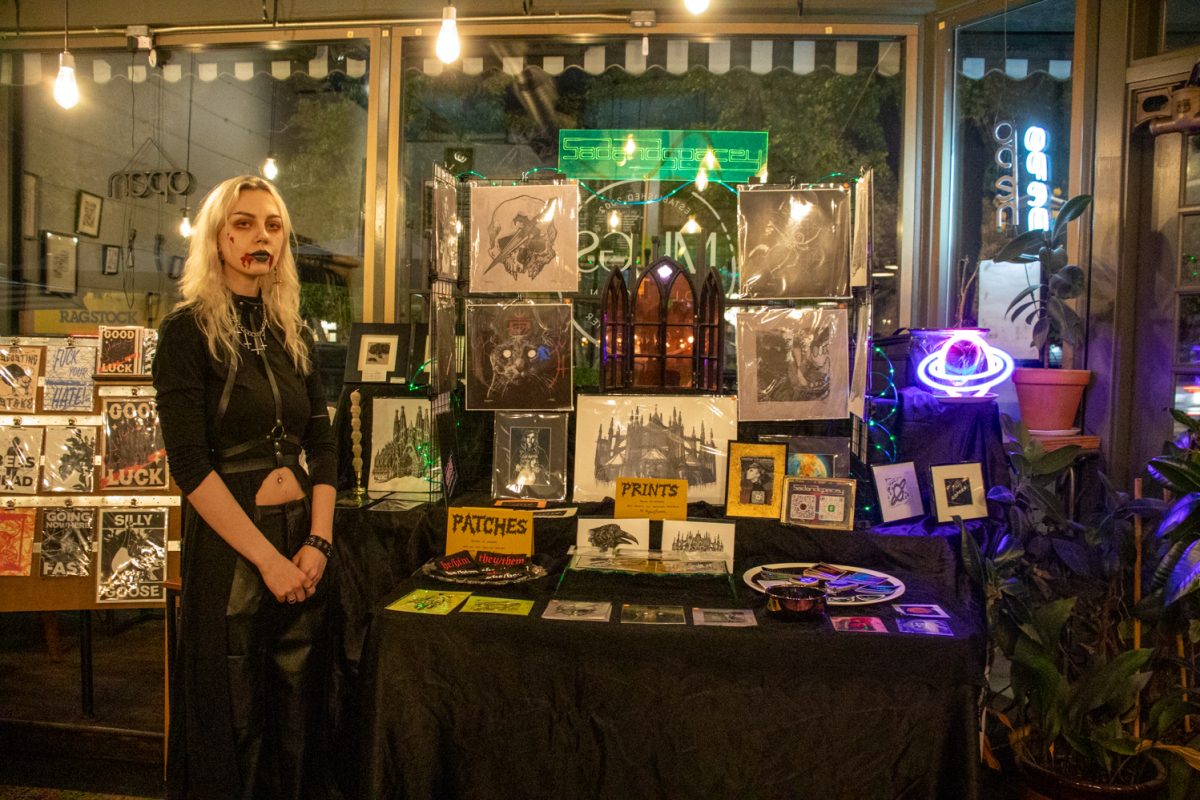 A person standing next to a table with prints and artwork for sale.