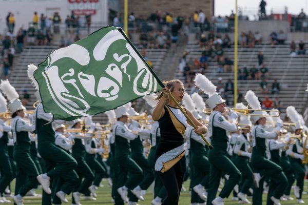 A girl waving a flag with a ram emblem on it performs with a band in the background.