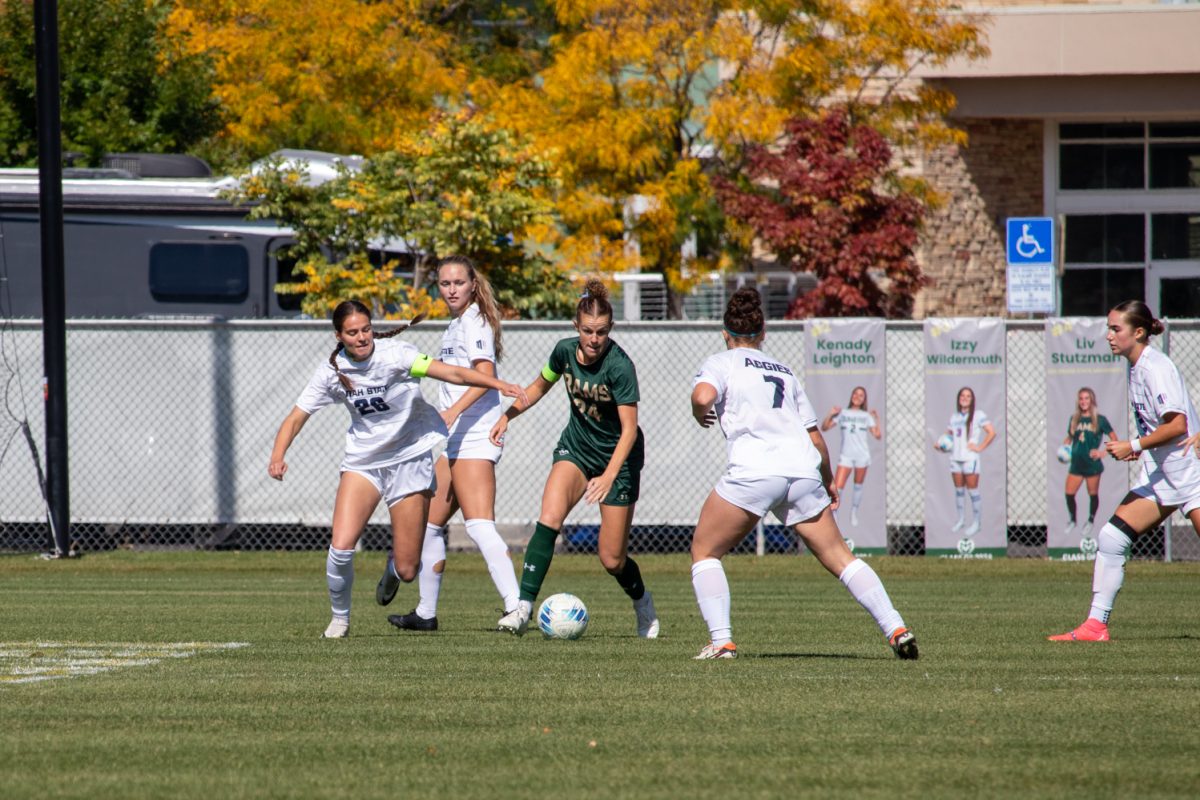 A person kicking a soccer ball, trying to avoid defenders.