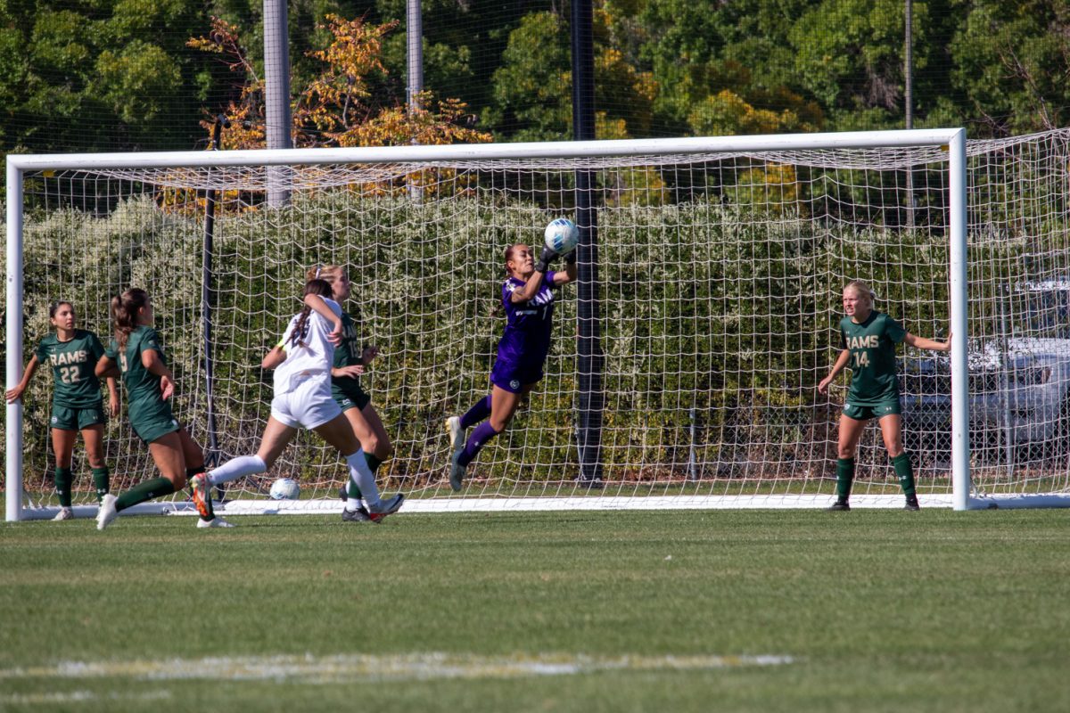A goalie jumping to catch a soccer ball.