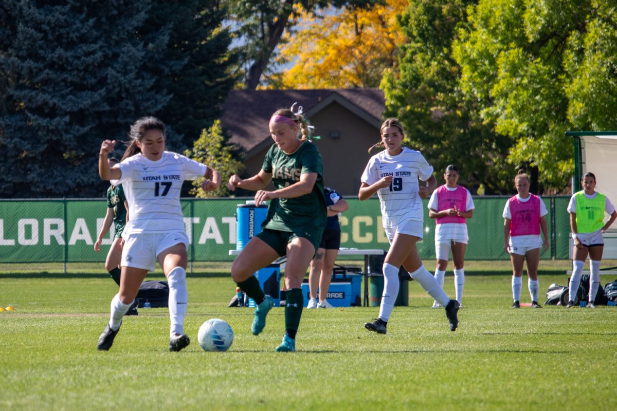 A soccer player kicking a ball away from a defender