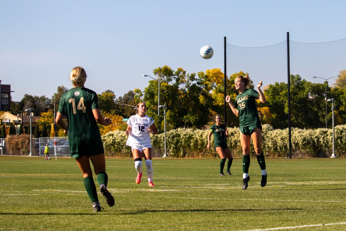 A soccer player jumps to hit the ball with her head.