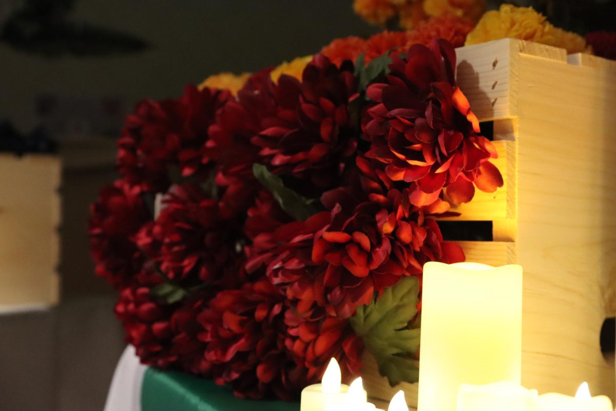 Red roses are lit by candlelight on a table honoring the life of a femicide victim in the Lory Student Center on Oct. 15 during Remembrance Roses: Honoring the Lives Lost to Femicide. 