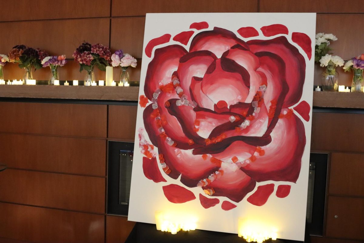 Candles line the wall with a painting illustration of a rose in front of the candles.