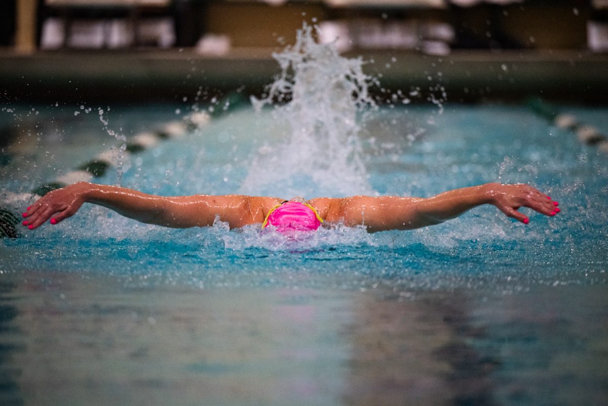 A swimmer's arms stretch out over the water while swimming butterfly.