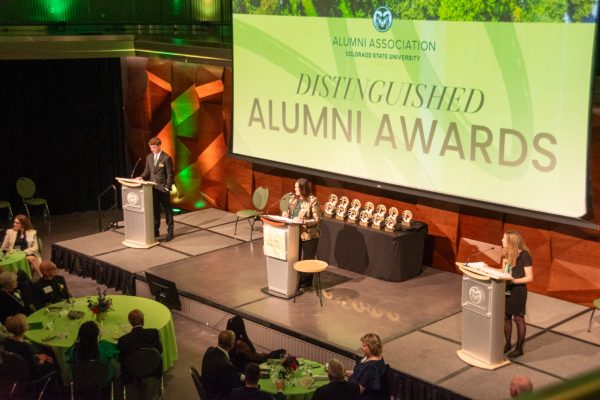 three podiums with different speakers with large sign in background that says "Distinguished Alumni Awards"