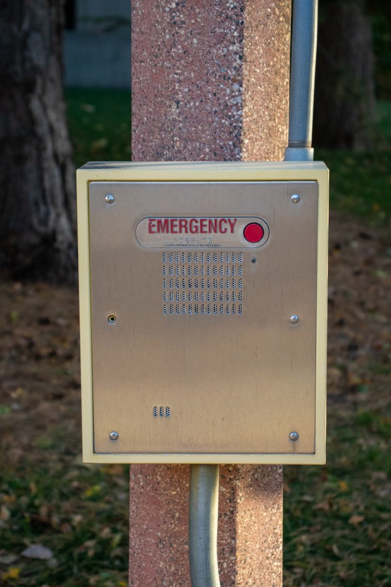 A box that says "emergency" with a red button and a speaker on a pole.