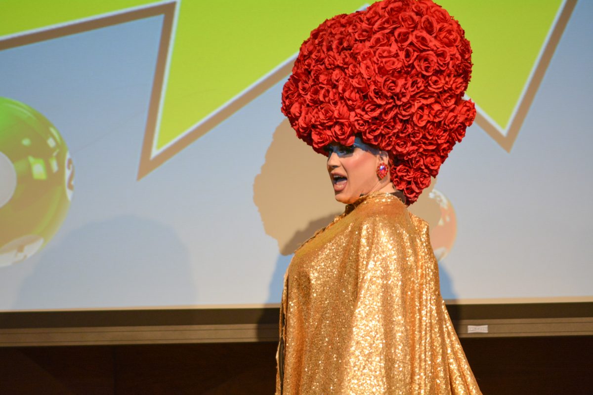 Performer in a gold cape with an extravagant rose headpiece