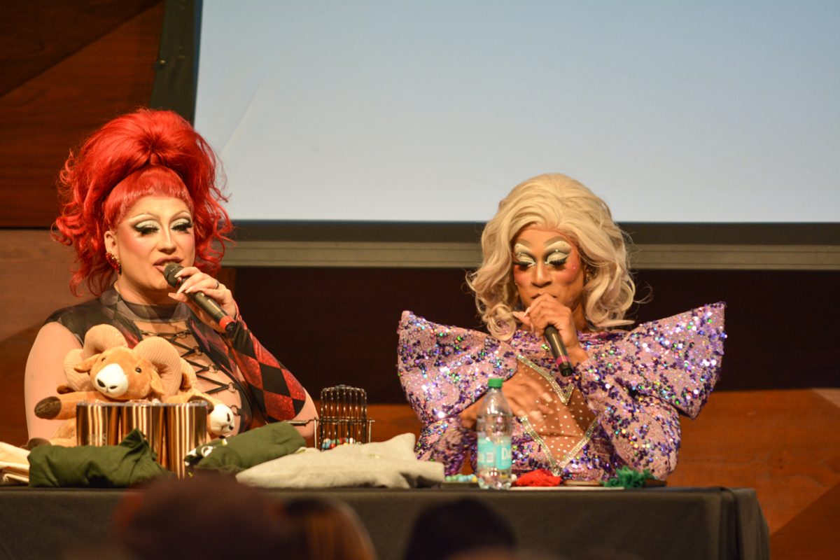 Two speakers with microphones sitting at a table