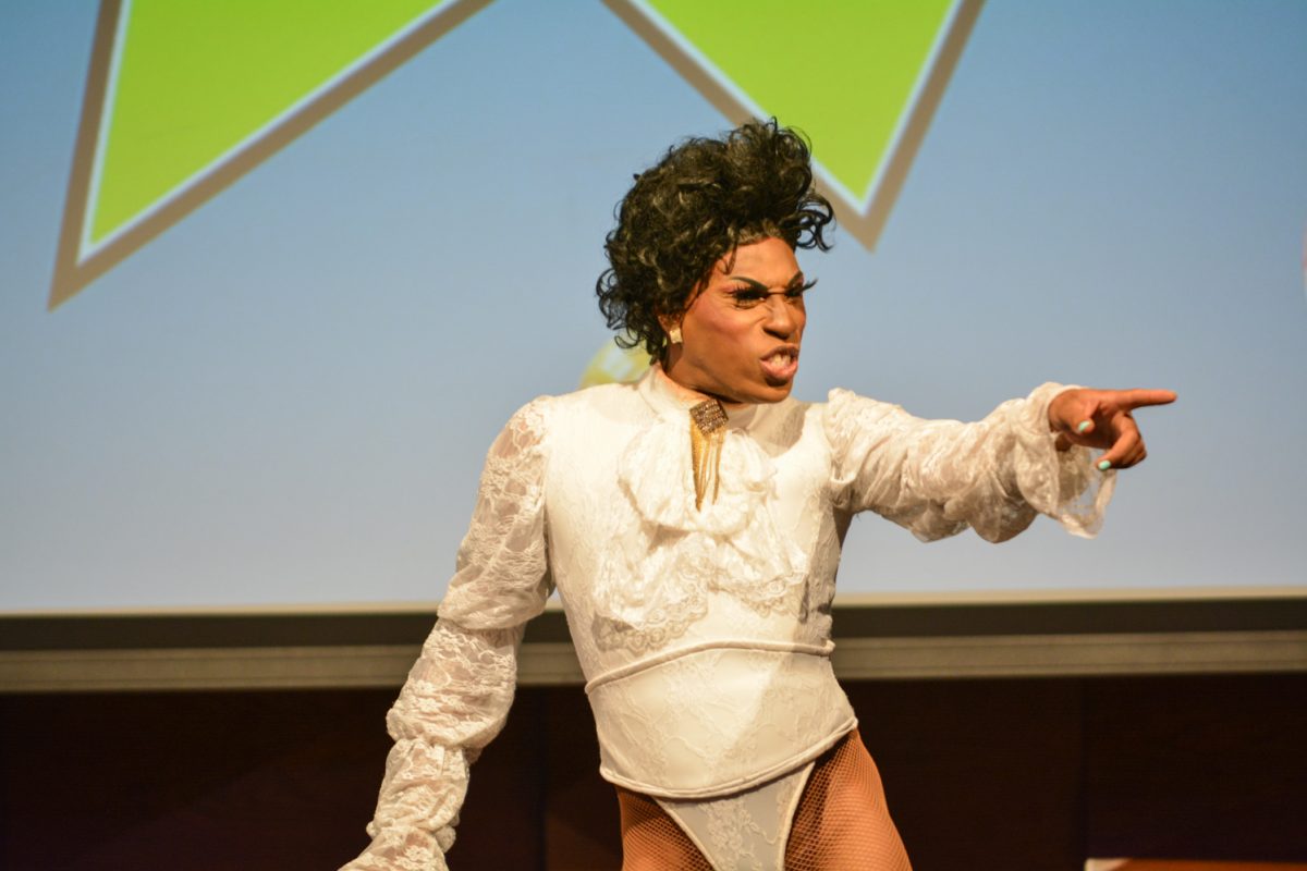 Performer in a white bodysuit pointing out to the crowd