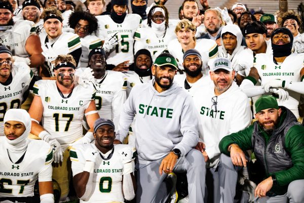 A large group of football players and coaches in white and green Colorado State uniforms pose for a photo.