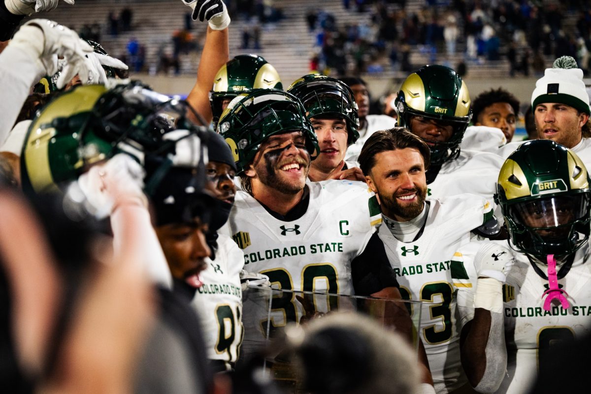 A crowd of smiling football players in white and green holding a trophy.