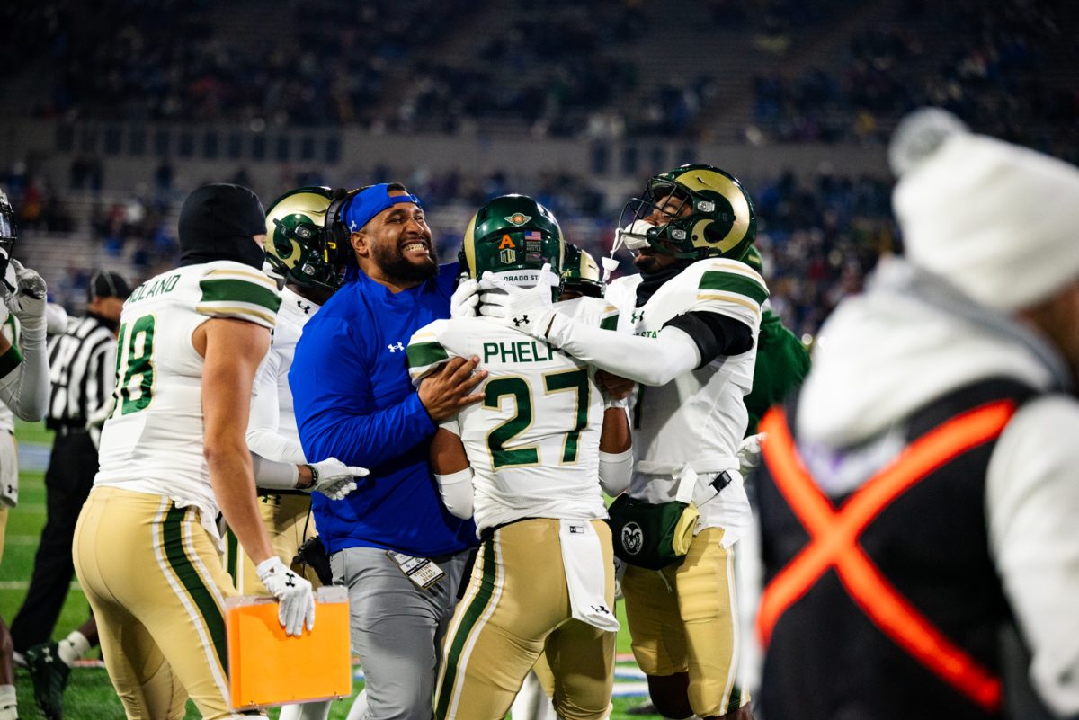 A football player in white and green hugs another player and a coach in blue.