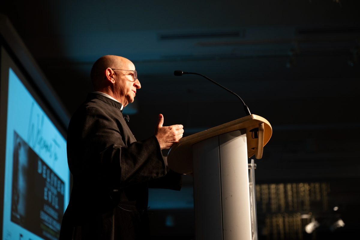 A priest speaks to a crowd at a podium.