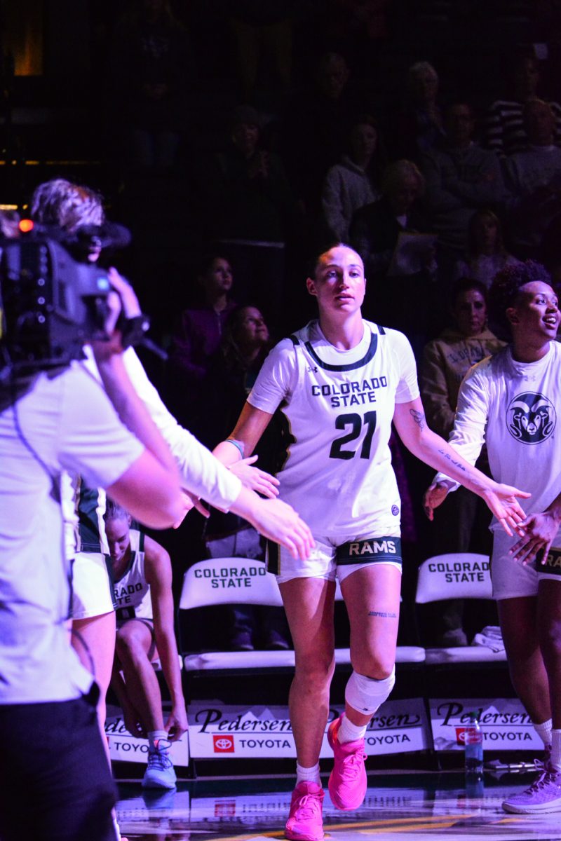 A player in a green and white jersey high fiving her teammates