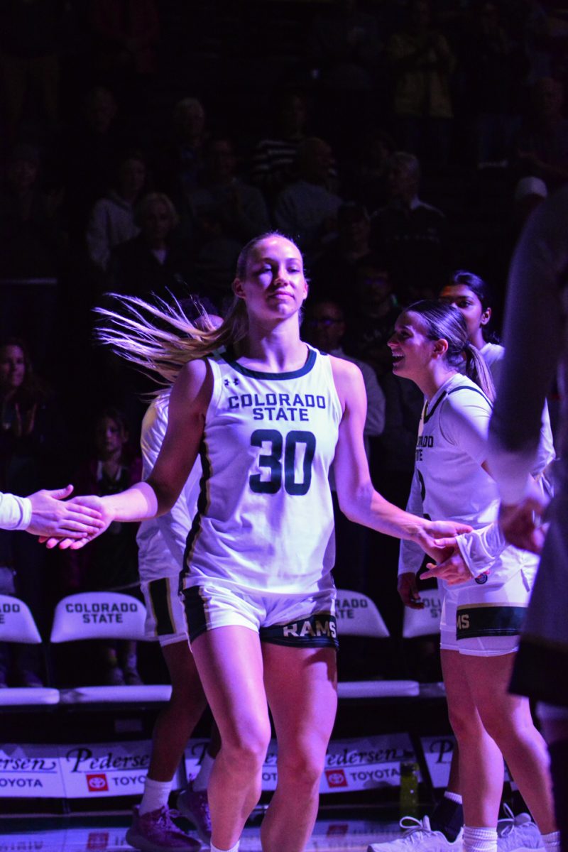 A player in a green and white jersey high fiving her teammates