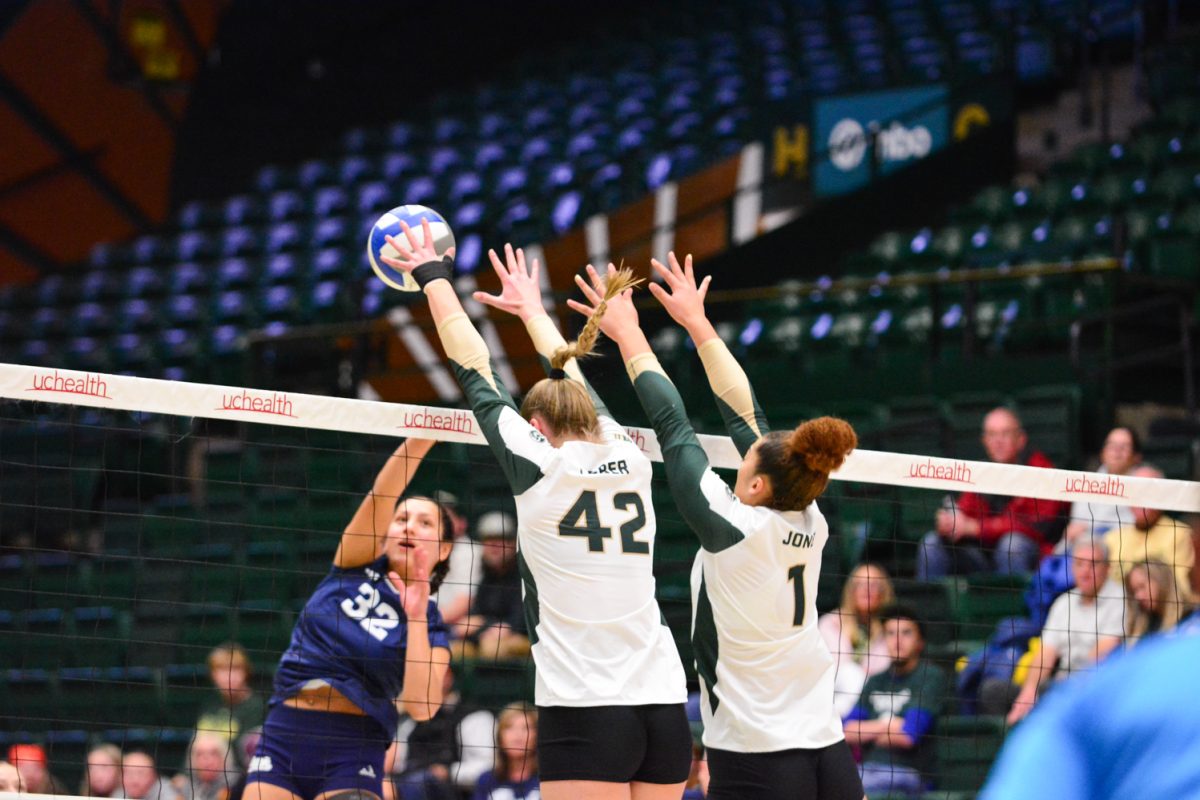 Two players in green and white jersey jumping and hitting the ball