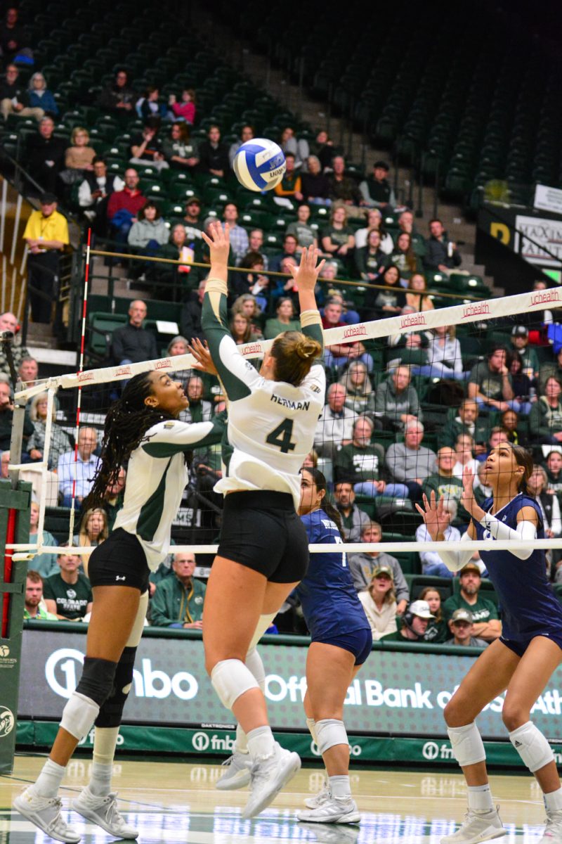 Two players in a green and white jerseys jumping for a ball