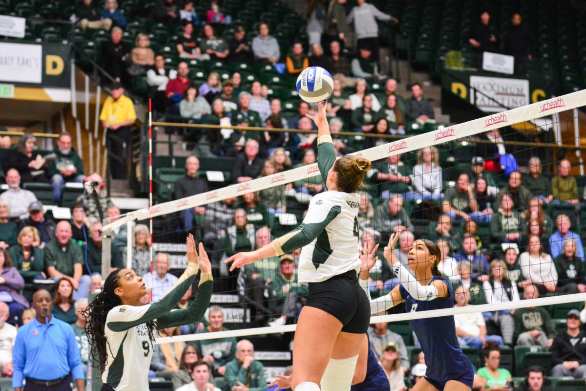 A girl in a green and white jersey jumping for the ball