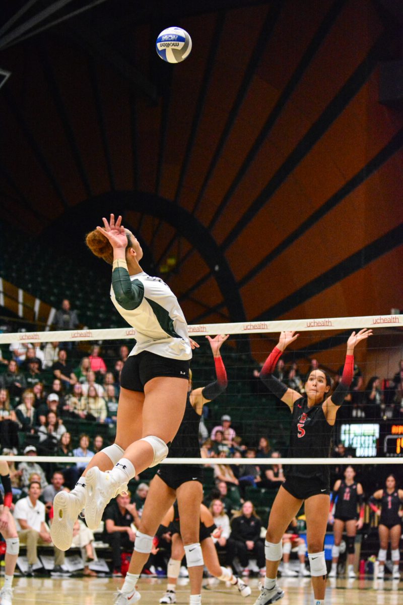 Girl in green and white jersey jumping up to hit the ball