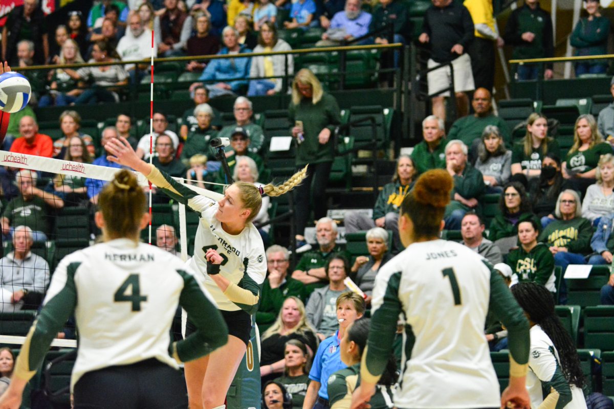 A girl in a green and white jersey hitting the ball