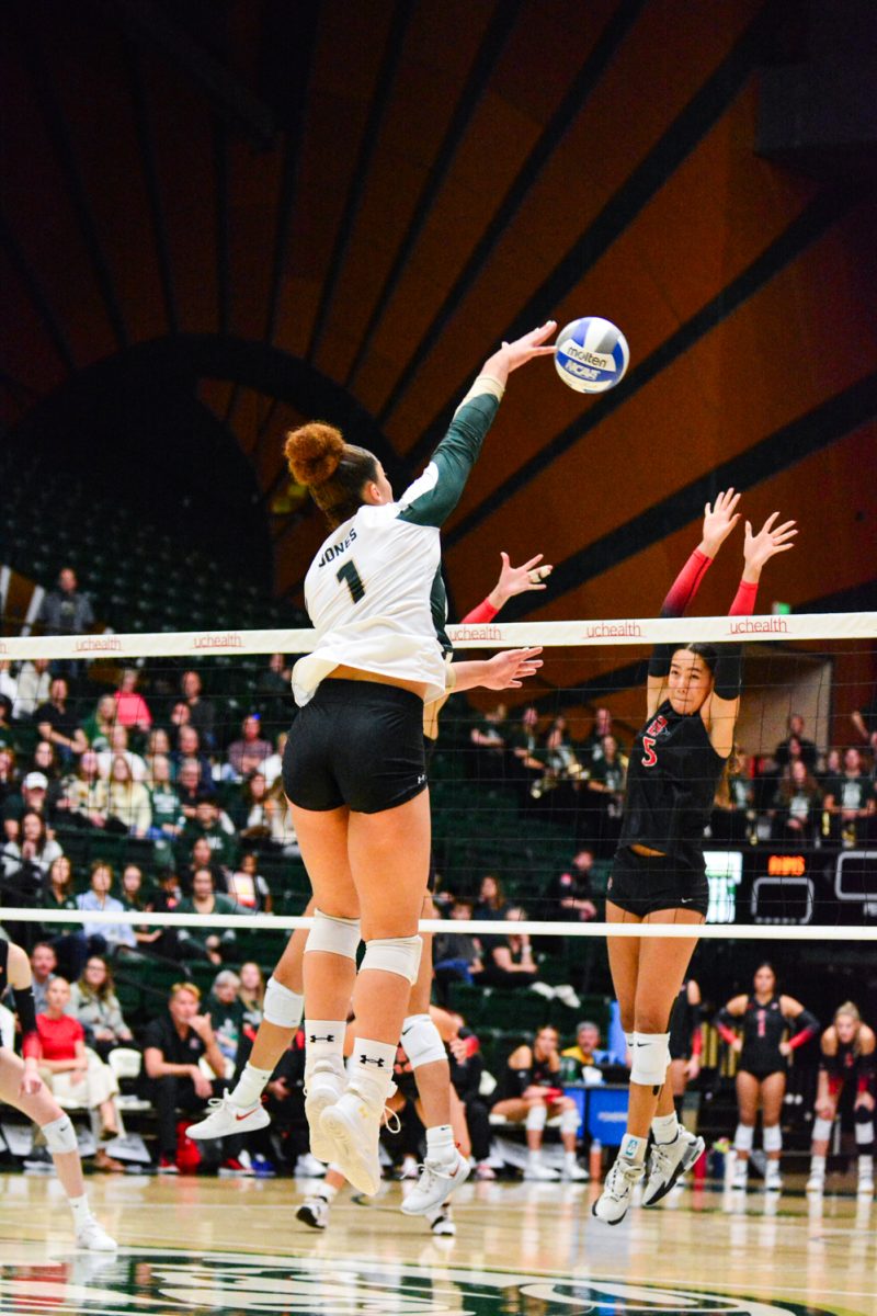 Girl in green and white jersey hitting the ball