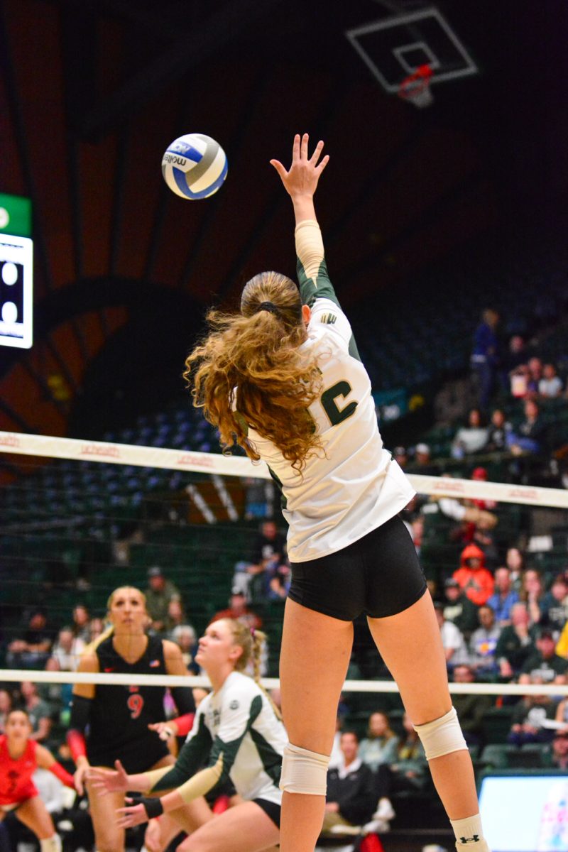 Girl in green and white jersey hitting the ball