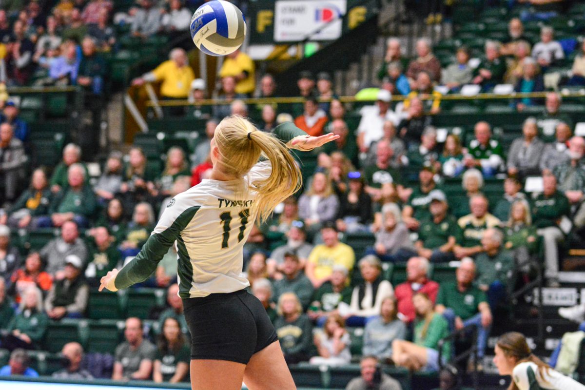 Girl in green and white jersey serving the ball