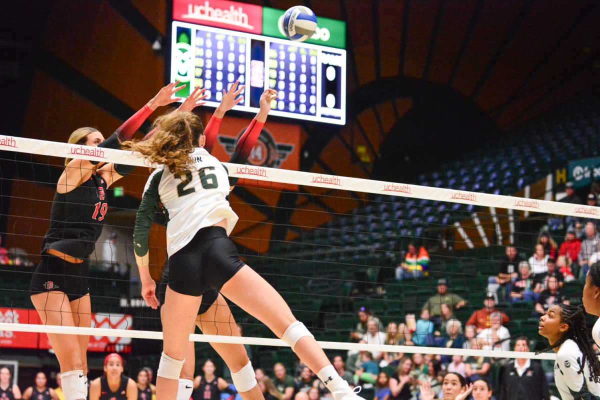 Girl in green and white jersey jumping after hitting the ball