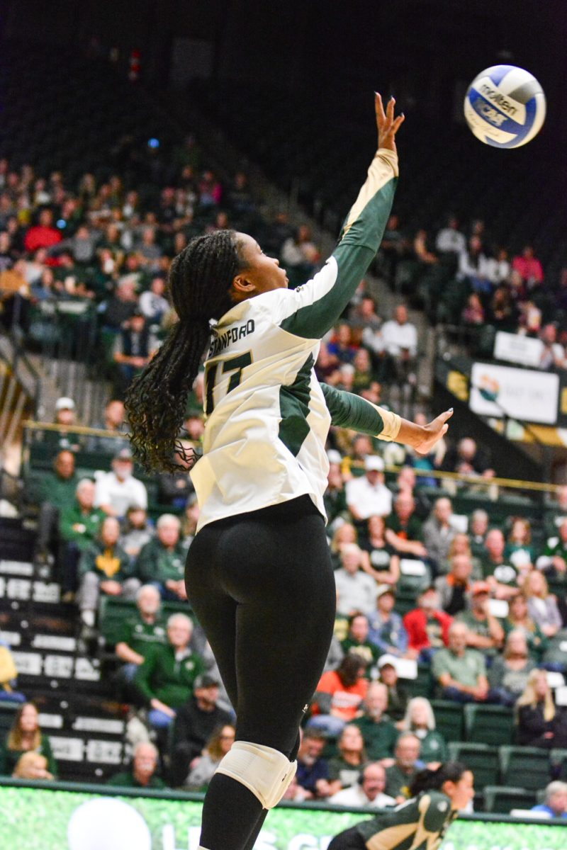 Girl in green and white jersey serving the ball