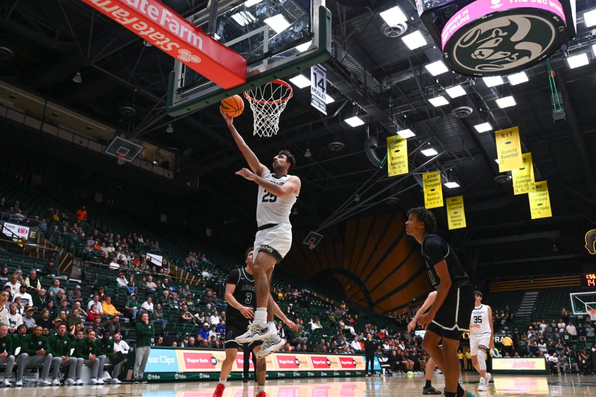 Photo of a basketball player in a white uniform jumps to throw a ball into a hoop.