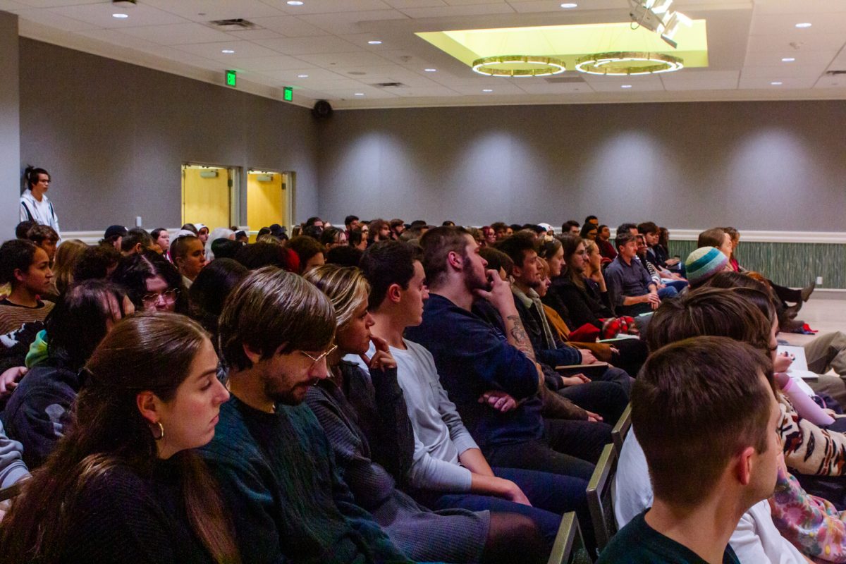 People sit in an audience, listening.
