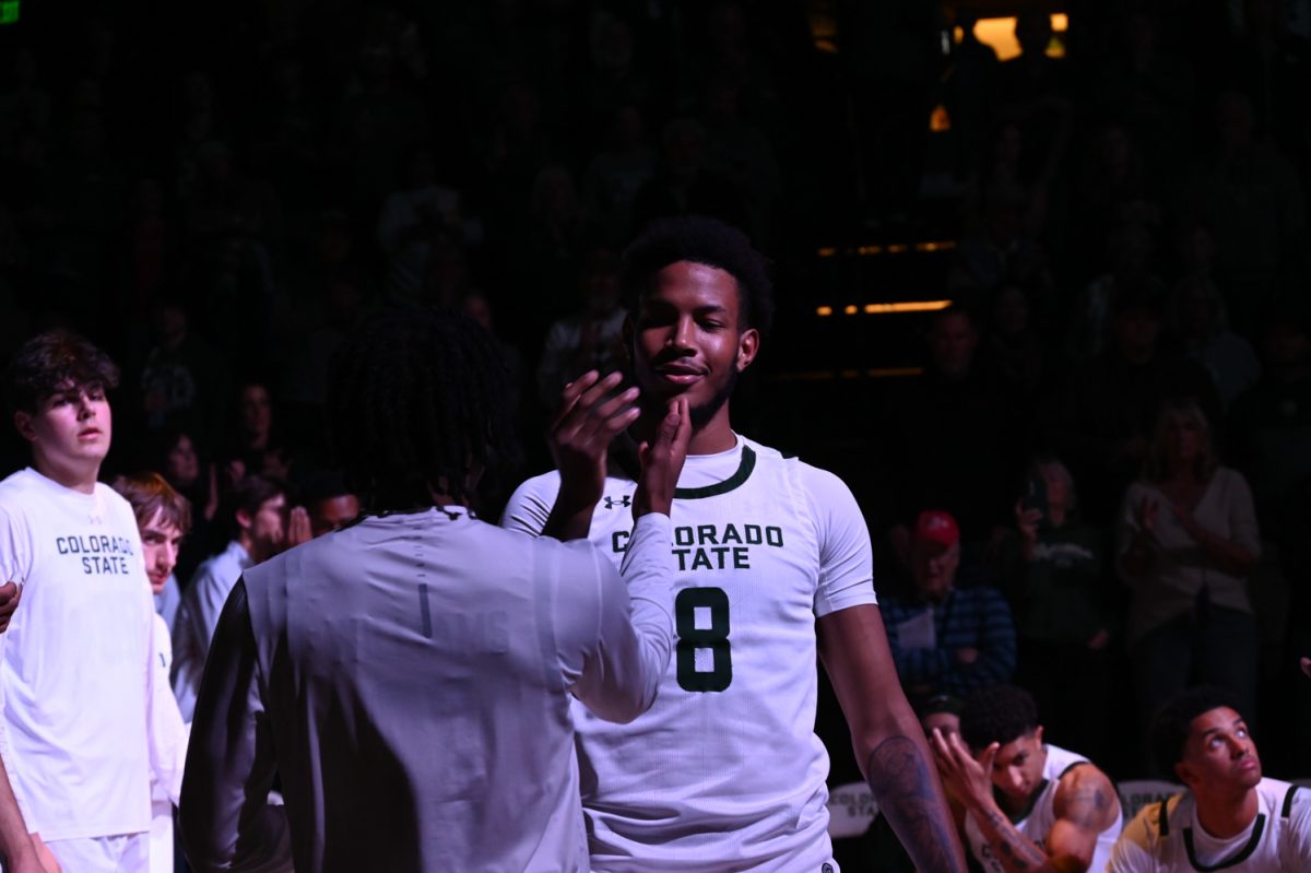 A player in a white uniform giving a high five to a player in a white long sleeve