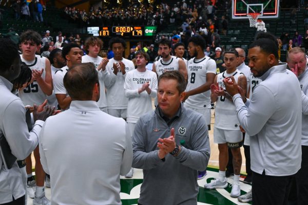 A group of men in white uniforms standing in a circle clapping