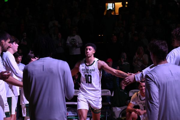 A player in a green and white uniform high fives teammates