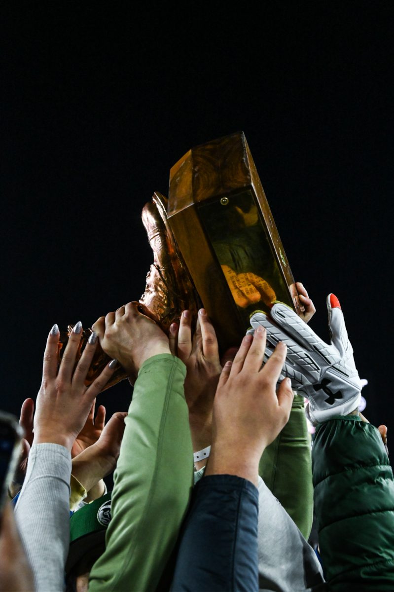 many hands holding a bronze boot trophy