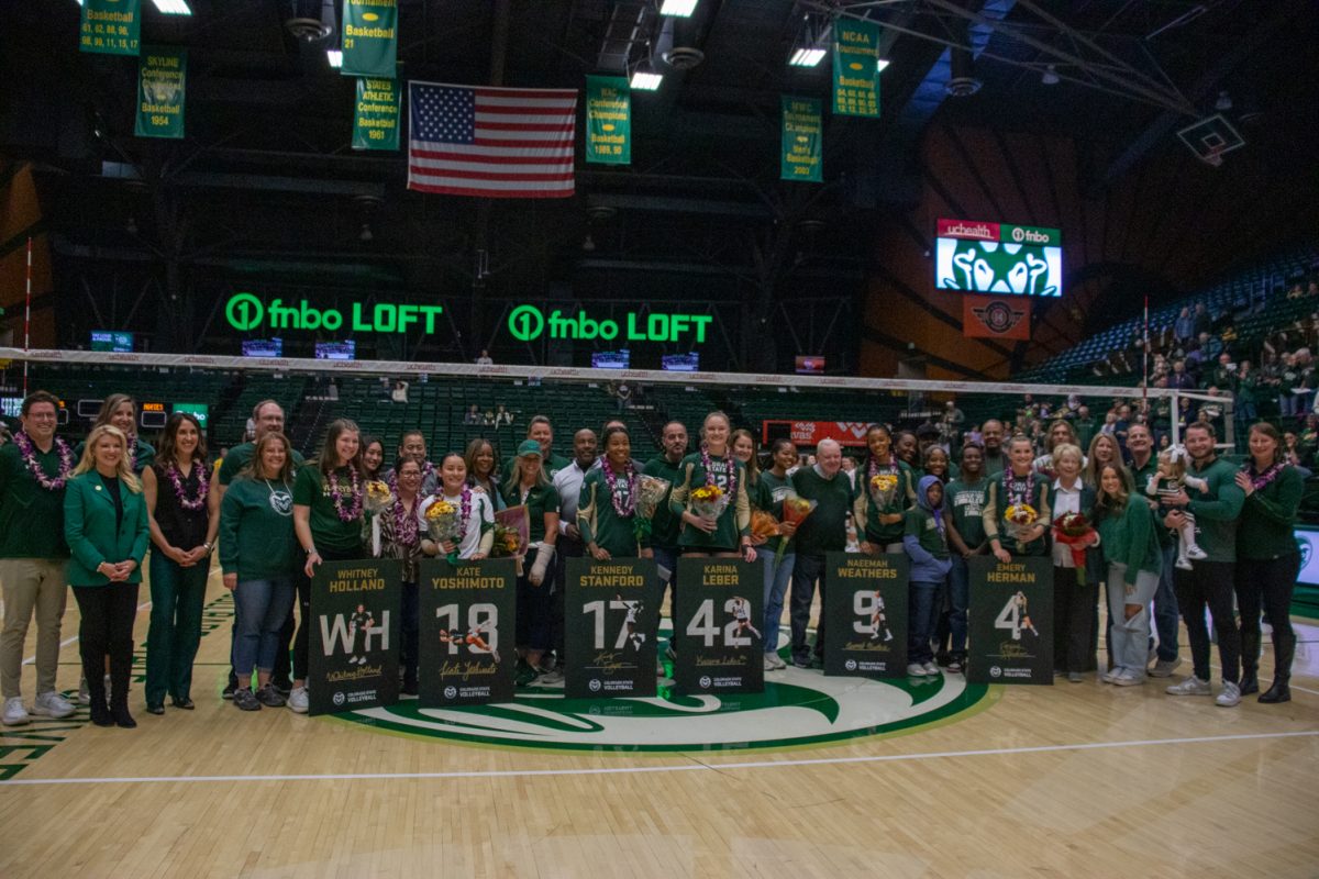 A group of volleyball players, their families, and coaches pose.