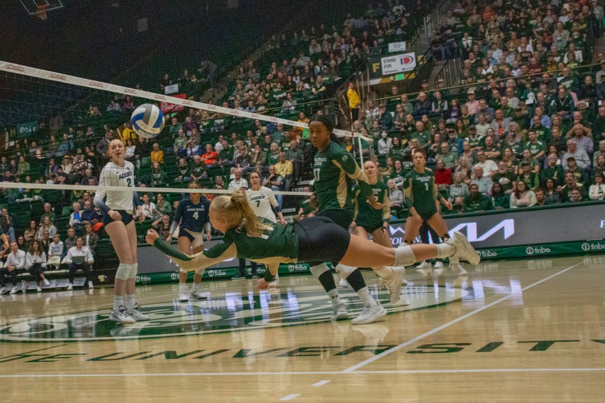 A volleyball player dives to keep the ball off the ground.