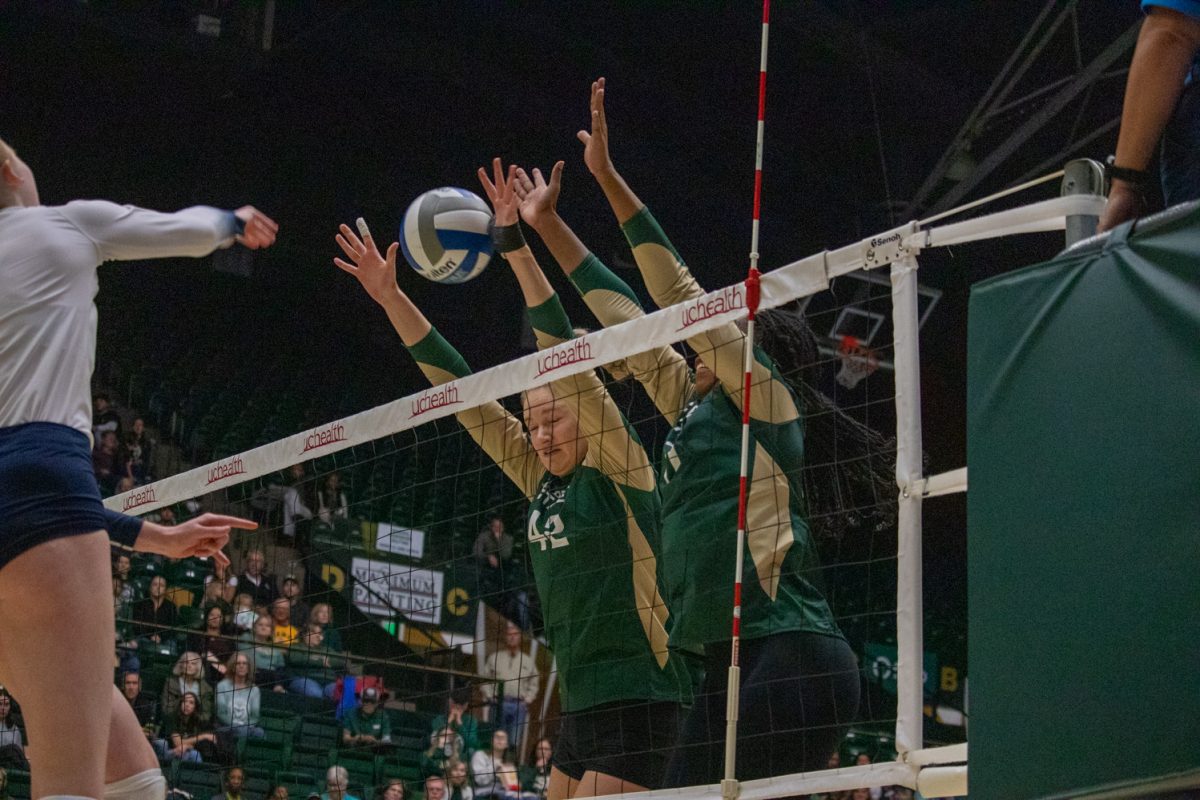 Two volleyball players block the ball.