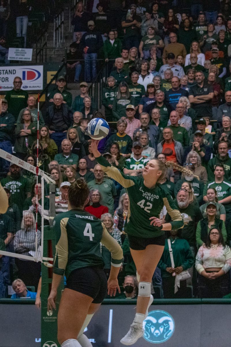 A volleyball player tips the ball over the net.