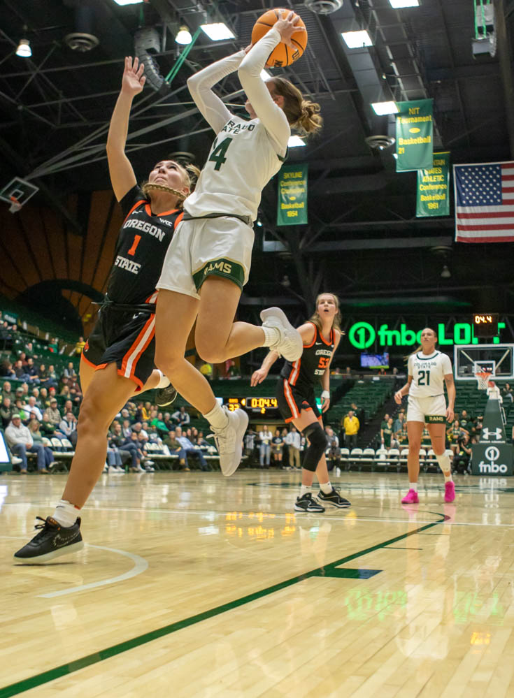 A woman in a white jersey jumps next to a woman in a black jersey at a sporting event.