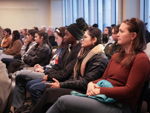 A crowd of people sit and listen to a speaker